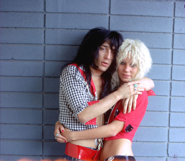 Colored photo of Sable Starr with Johnny Thunders hugging and looking at the camera.