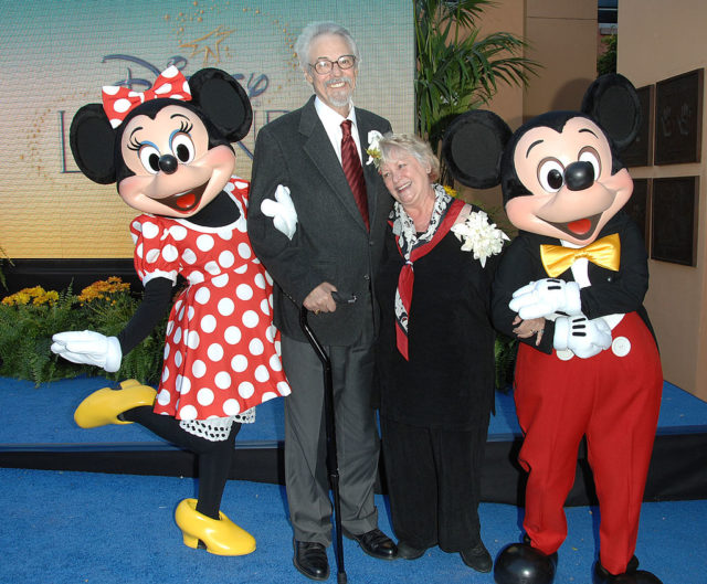 Colored photo of Mickey and Minnie Mouse standing with Wayne Allwine, the voice of Mickey, and Russi Taylor, the voice of Minnie Mouse.