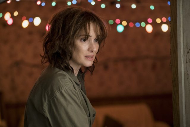 Colored movie still of Winona Ryder as Joyce Byers in Stranger Things. She has short hair and bangs.