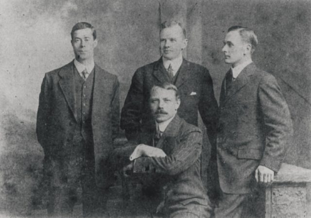 Black and white photo of the four surviving officers of the Titanic wearing suits: Harold Lowe, Charles Lightoller, Joseph Boxhall, Herbert Pitman.