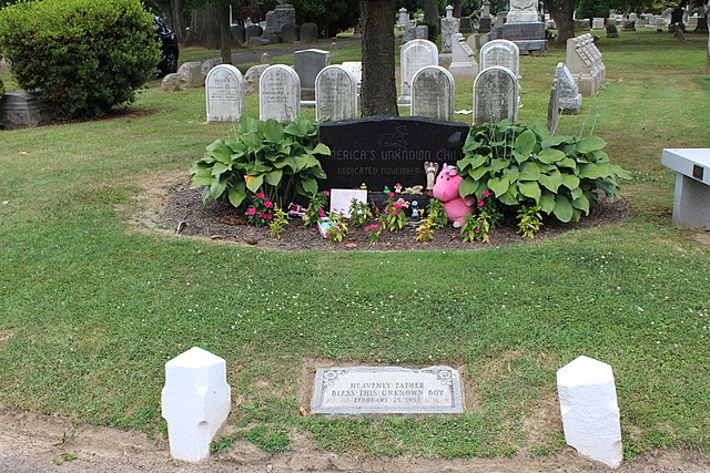Gravestone of the Boy in the Box, surrounded by flowers and bushes