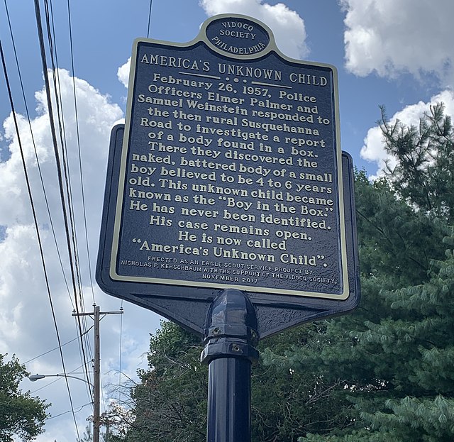 Blue metal sign located outside of a wooded area