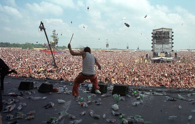 Crowd throwing water bottles at Kid Rock while he performs on stage at Woodstock '99