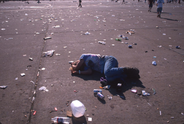 Festival-goer lying on the pavement among litter