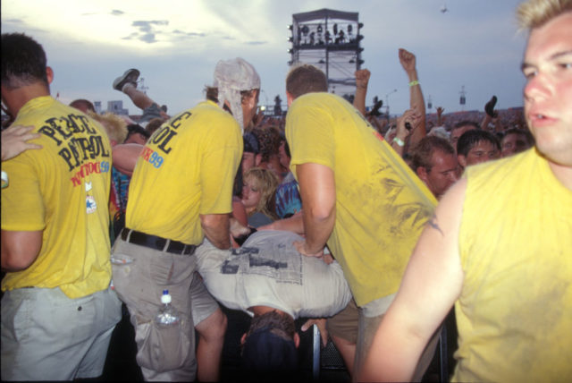 Peace Patrol workers lift an unruly concert goer over a barricade 