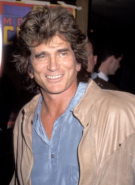 Colored photo of Michael Landon smiling at the camera in a blue shirt and tan jacket.