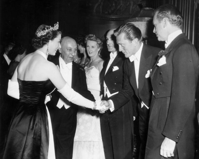 Kirk Douglas shaking hands with Queen Elizabeth II, while Douglas Fairbanks Jr. watches