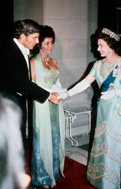 Queen Elizabeth II shaking John Warner's hand while Elizabeth Taylor watches