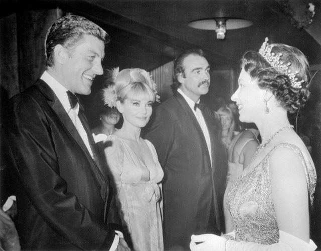 Dick Van Dyke, Diane Cilento and Sean Connery standing in front of Queen Elizabeth II