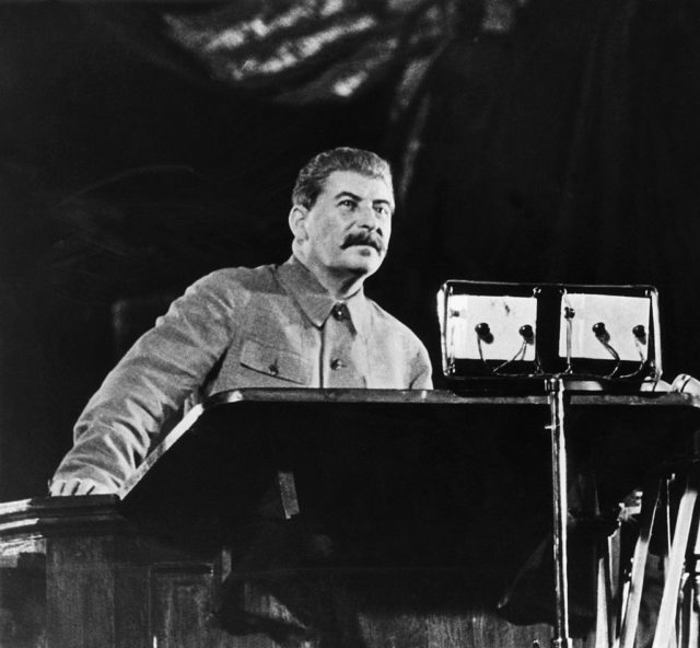 Joseph Stalin speaks at a podium 