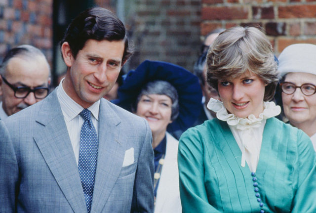 Colored photo of Prince Charles in a suit standing beside Princess Diana in a high neck white shirt with green jacket.