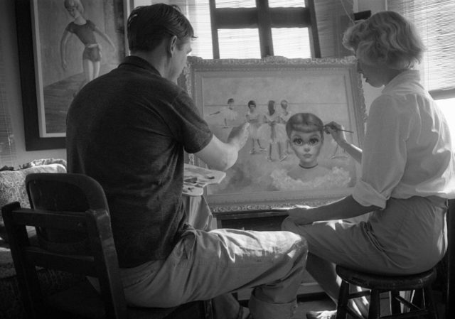 Black and white photo of Walter and Margaret Keane sitting together painting.