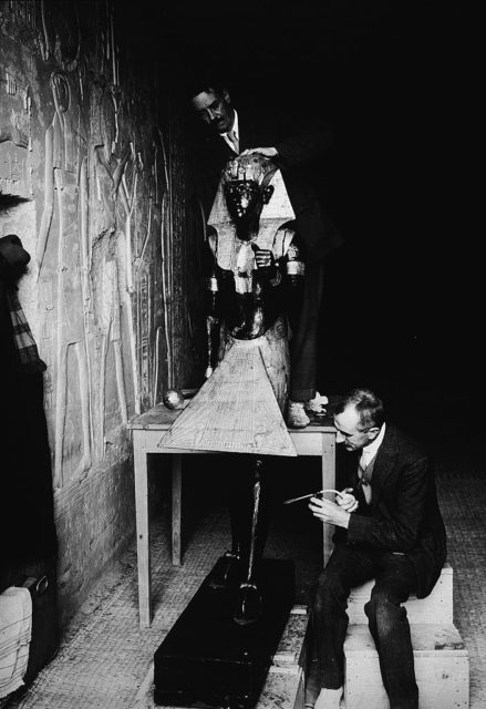 Black and white photo of men moving a statue of King Tut out of a tunnel.