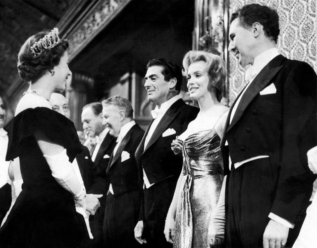 Queen Elizabeth II standing in front of Marilyn Monroe and a row of men