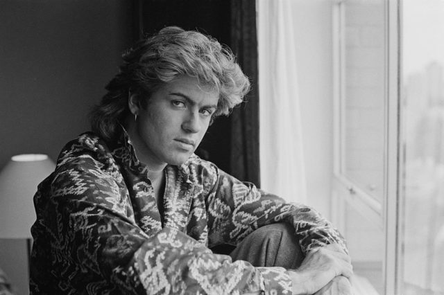 Black and white photo of George Michael little with his arms around his knee.