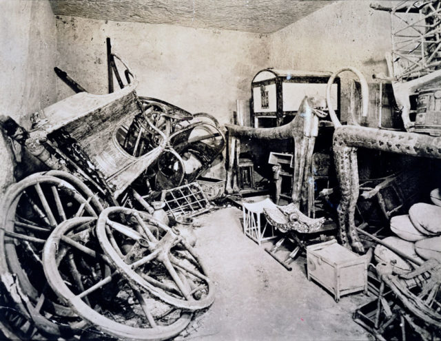 Black and white photo of piles of objects against the walls of the antechamber in King Tut's tomb.