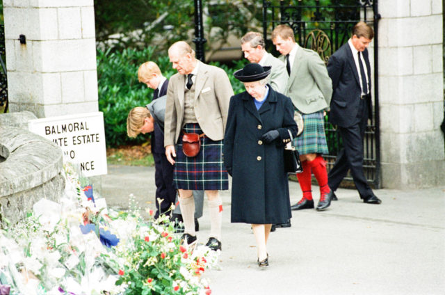 Colored photo of the Royal family looking at flowers for Princess Diana at the gates of Balmoral Castle.