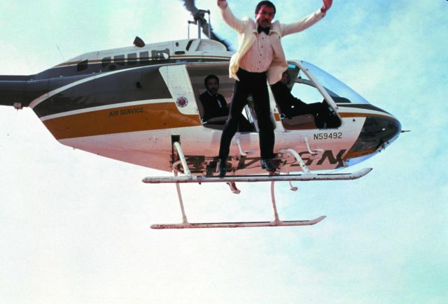 Burt Reynolds leaps from a helicopter in a suit