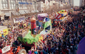 Colored photo of floats moving through a large crowd during a Mardi Gras Parade in New Orleans
