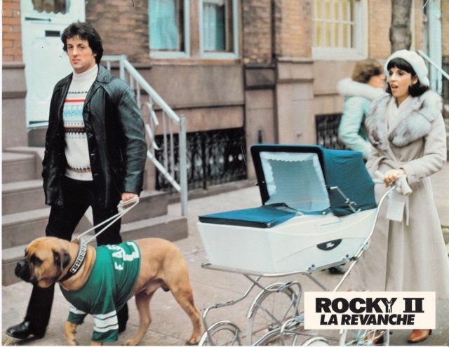 Talia Shire pushing a baby stroller beside Sylvester Stallone and a dog in the movie 'Rocky II.'