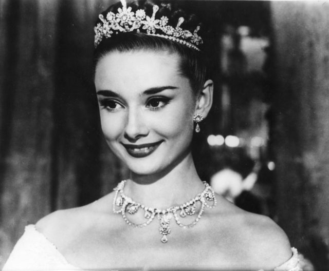 Black and white photo of Audrey Hepburn smiling while wearing a tiara in 'Roman Holiday.'