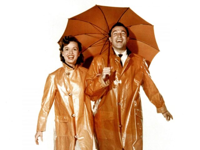A still from Singin' in the Rain features Debbie Reynolds and Gene Kelly in rain gear