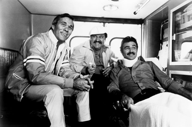 Hal Needham, Dom DeLuise, and Burt Reynolds (sporting a neck brace) in a trailer while filming The Cannonball Run
