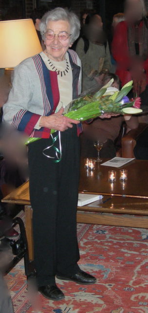 Colored photo of Ursula Franklin smiling at the camera while holding a bouquet of flowers.