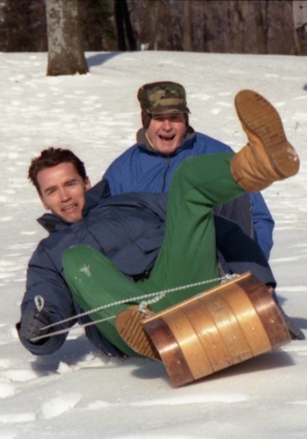 Arnold Schwarzenegger and George H.W. Bush sledding together.