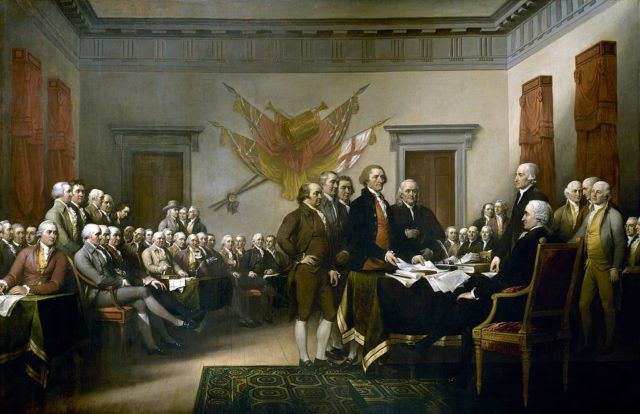 Group of men gather around a table to show the Declaration of Independence to the US Congress.
