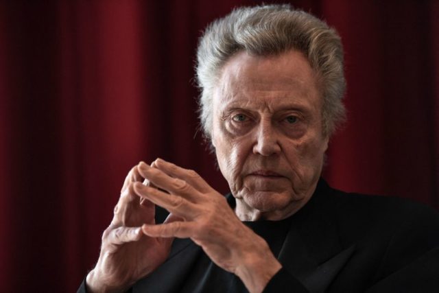 Christopher Walken staring at the camera with his fingers pressed together.