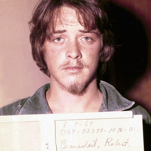 Robert Beausoleil holding up a card for his mug shot.