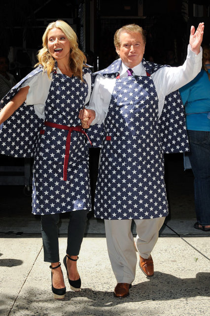 Regis Philbin and Kelly Ripa holding hands while wearing matching polka dot aprons and capes.