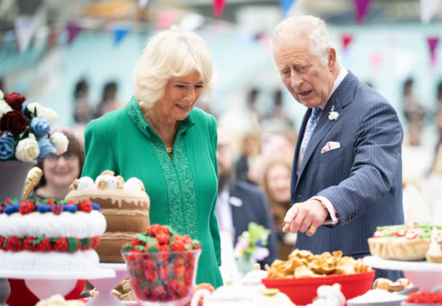 Charles and Camilla look over a table of desserts 