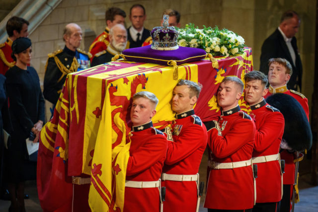 Military bearers carry the coffin of Queen Elizabeth II draped in a flag.