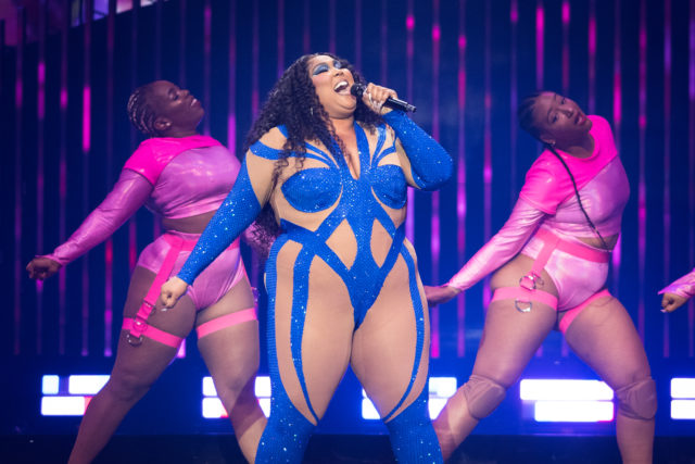 Lizzo performing on stage with two backup dancers
