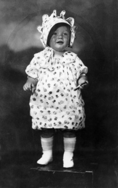 An infant Marilyn Monroe standing on a wooden stool