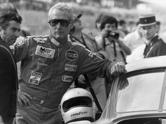 Paul Newman leaning against a race car