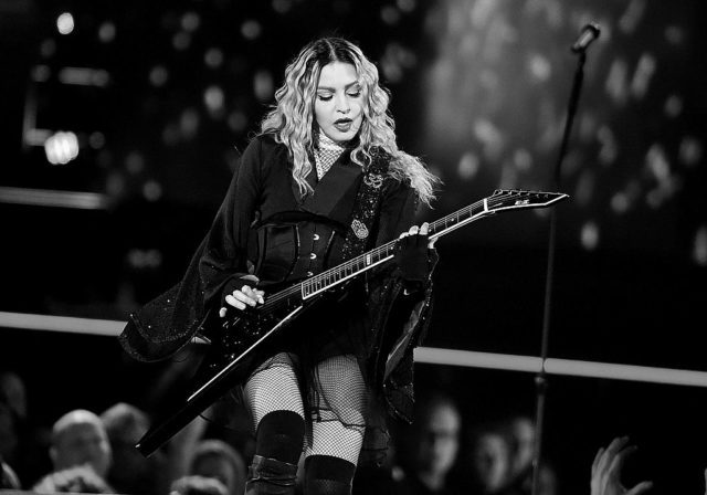 Madonna plays guitar while performing on stage