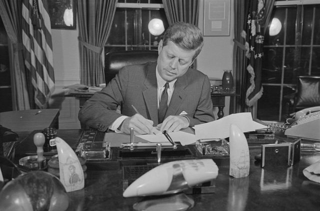 John F. Kennedy signs a proclamation from the Oval Office