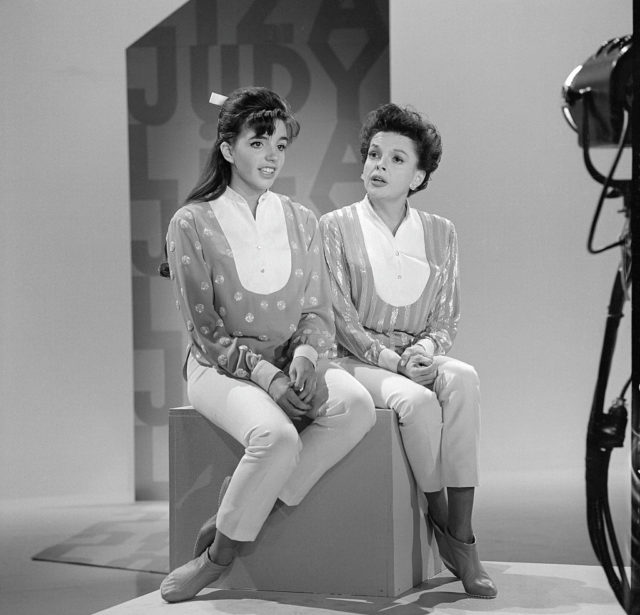 Judy Garland and Liza Minnelli wearing matching outfits siting on a box.
