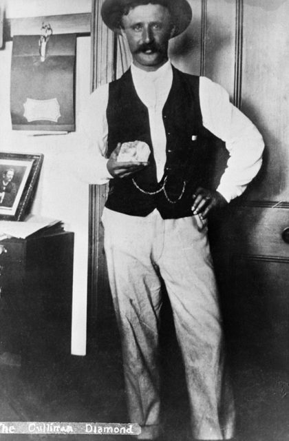 Miner in a black vest with his hand on his hip holds the Cullinan diamond.