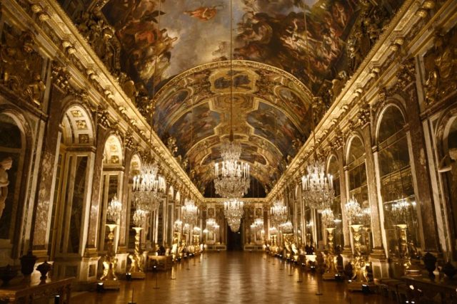 Hall of Mirrors in Versailles, decorated with elaborate gold and chandeliers. 