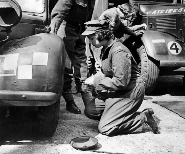 Princess Elizabeth changes a tire in military uniform during WWII