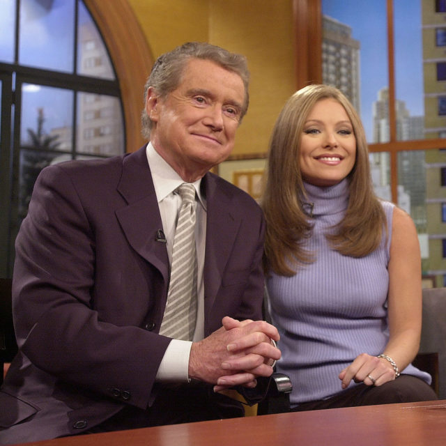 Young Regis Philbin and Kelly Ripa sit smiling beside each other .