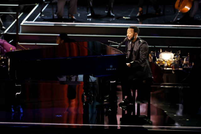 John Legend playing piano on stage at the Emmys