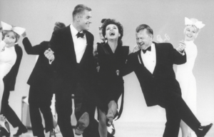Judy Garland in a black dress dancing in a line with Mickey Rooney and Jerry Van Dyke.