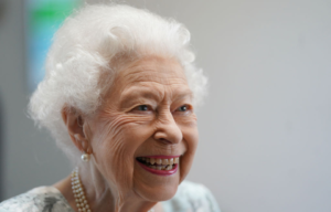 Queen Elizabeth II wearing pink lipstick smiling at the camera.