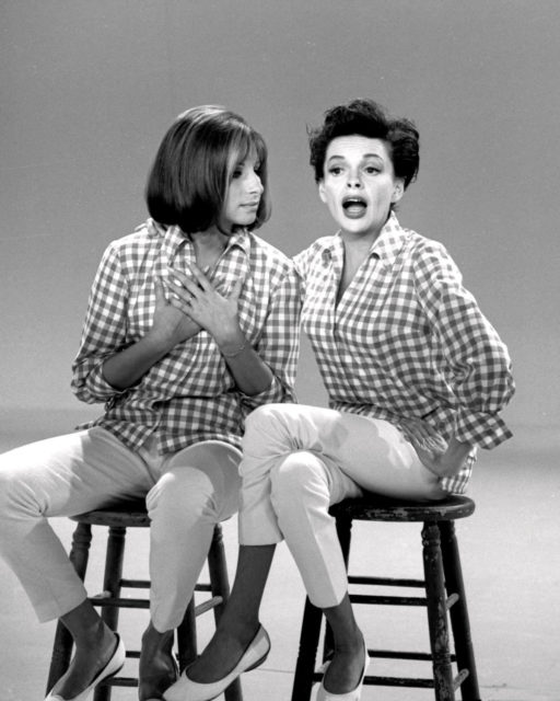 Judy Garland and Barbra Streisand sitting on stools in matching plaid shirts. 