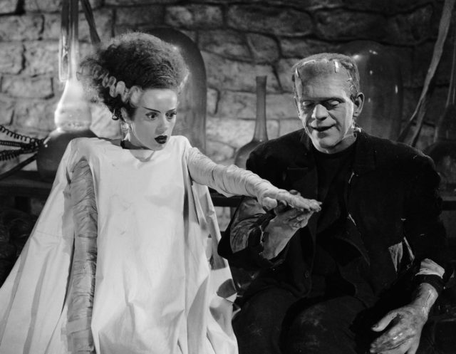 The Monster and the Bride of Frankenstein Monster holding hands outstretched